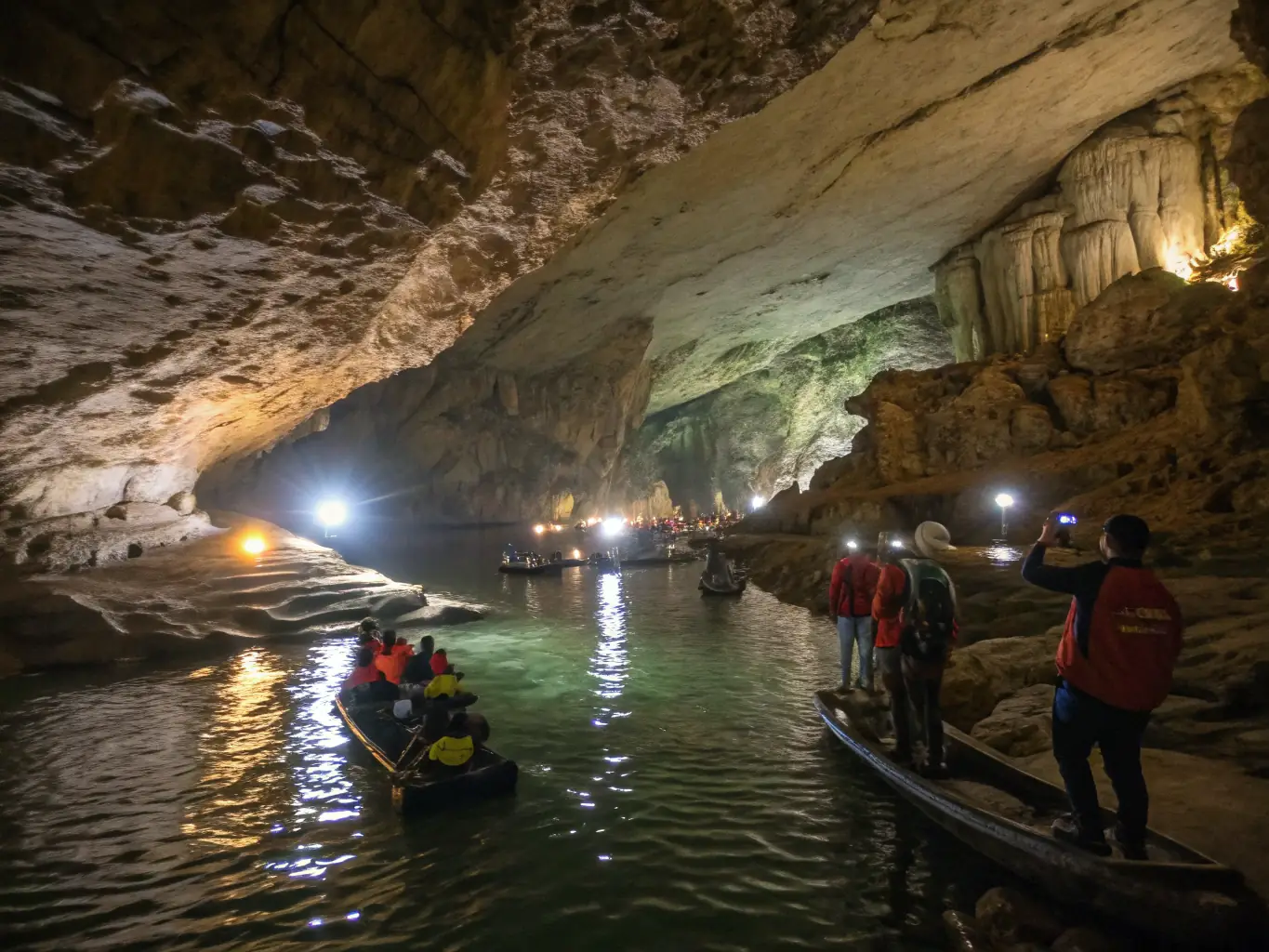 A group of children and adults exploring a prehistoric cave with guides pointing out ancient drawings and artifacts, showcasing an educational tour at PSF Prehisto Site de Foissac.
